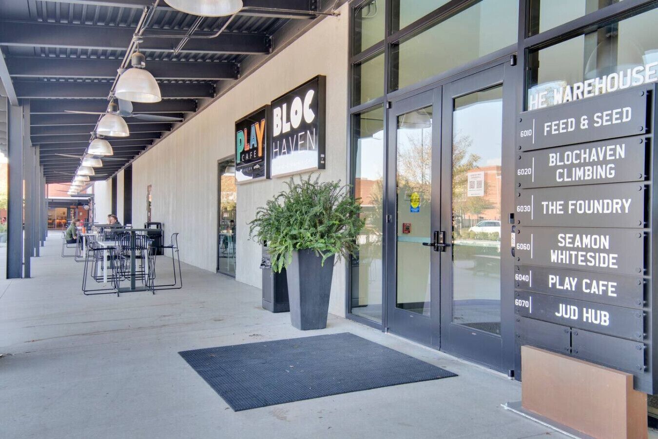 Ein modernes Gebäude mit Schildern für 'Play Cafe', 'Jud Hub' und 'Feed & Seed'.