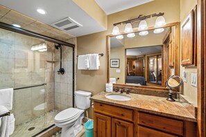 A bathroom with a glass shower enclosure, a toilet, a sink with a vanity, and a large mirror. - Après-Ski Hideaway | Hot Tubs, Fire & Ski Shuttle (Steamboat Springs)