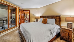 Camera da letto con un letto grande, una testiera in legno, un comodino e una porta scorrevole in vetro che dà su un balcone.