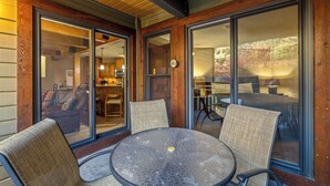 Una veranda coperta con un tavolo rotondo e due sedie, ampie porte scorrevoli in vetro e vista sull'interno.