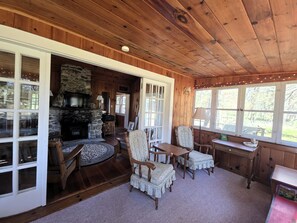 L’intérieur d’un chalet en bois, avec une cheminée en pierre, un coin repas et un espace salon confortable.