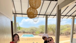 Ein Holztisch mit Speisen und Getränken, unter einem überdachten Bereich mit Blick auf einen Pool und eine Wüstenlandschaft.
