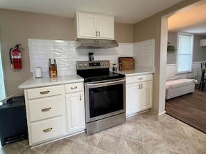 A modern kitchen with white cabinetry, a stainless steel oven, and a built-in microwave.
