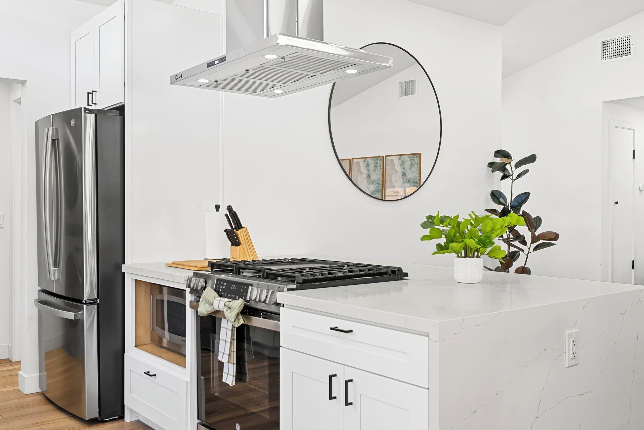 A modern kitchen with a stainless steel refrigerator, a built-in oven, and a gas stove.