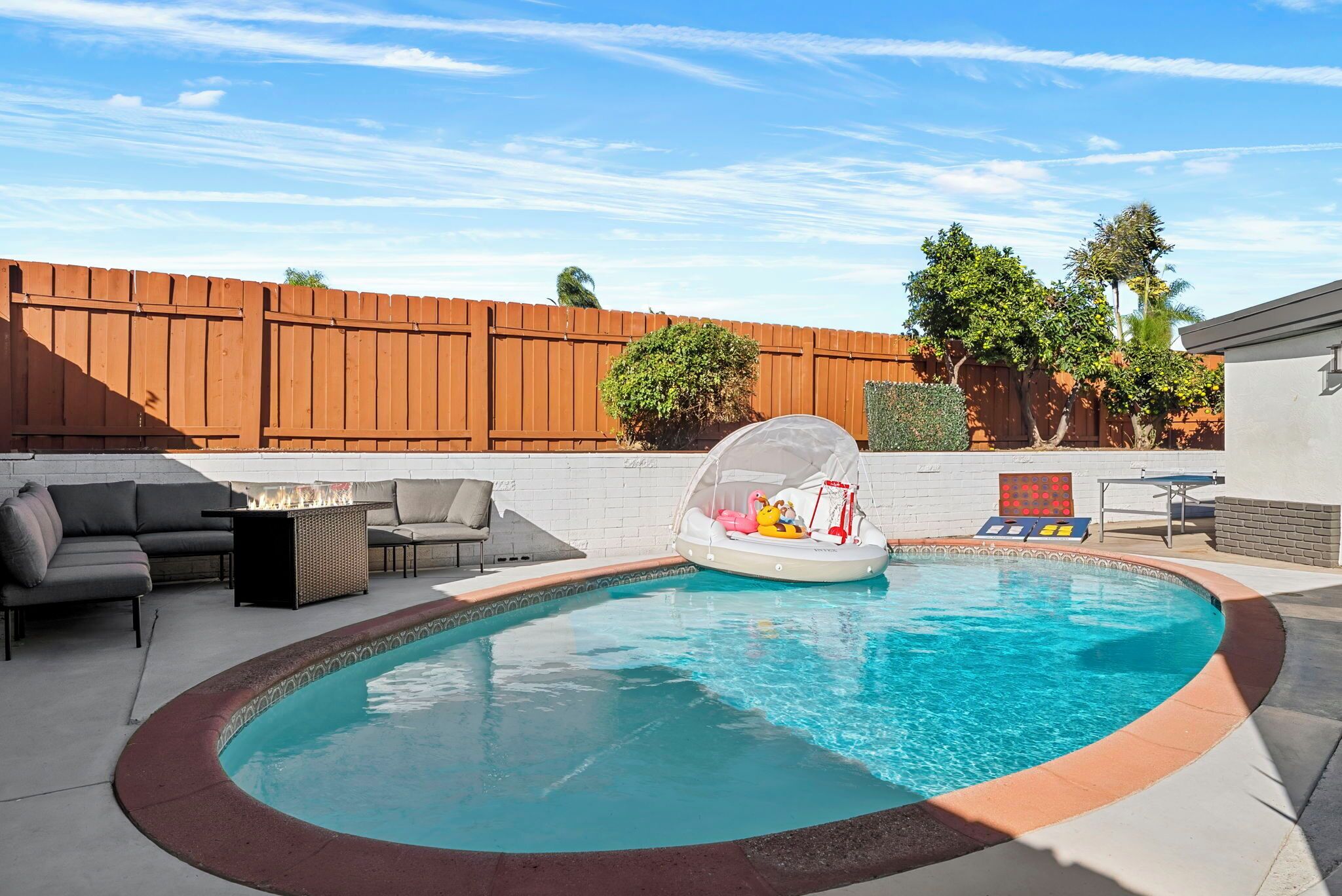 A backyard with a swimming pool, a fire pit, and outdoor furniture.
