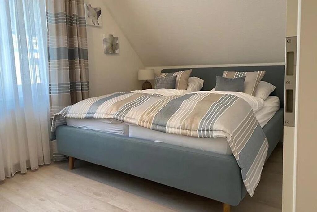 Une chambre à coucher avec un lit, des rideaux, une table de chevet et une lampe fixée au mur.