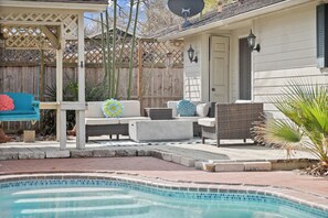 Un patio trasero con piscina, muebles de exterior y valla de madera.