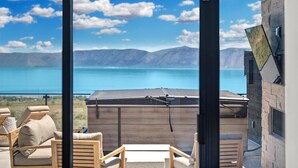 Una habitación moderna con un ventanal grande que da a un lago y montañas.