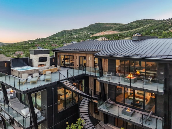 A modern multi-story house with a rooftop deck, a spiral staircase, and large windows.
