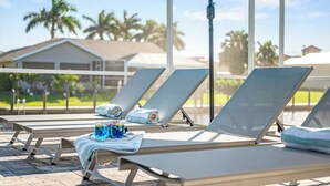 A poolside area with sun loungers, towels, and drinks. - Allure - Luxury Rental in Walking Distance to Cape Coral Yacht Club (Cape Coral)