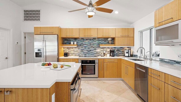 A modern kitchen with wooden cabinets, a white countertop, a built-in oven, and a ceiling fan. - Allure - Luxury Rental in Walking Distance to Cape Coral Yacht Club (Cape Coral)