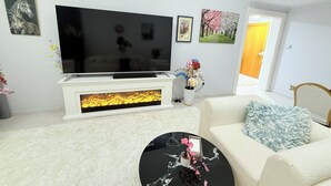 Un salon doté d’un téléviseur à écran plat, de canapés blancs, d’une table basse et d’objets décoratifs.