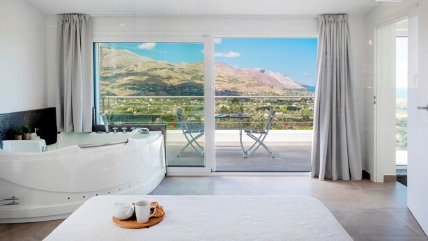 A modern bathroom with a bathtub, a vanity, and a large window offering a scenic mountain view. - Villa dei Sospiri 4, Emma Villas (Castellammare del Golfo)
