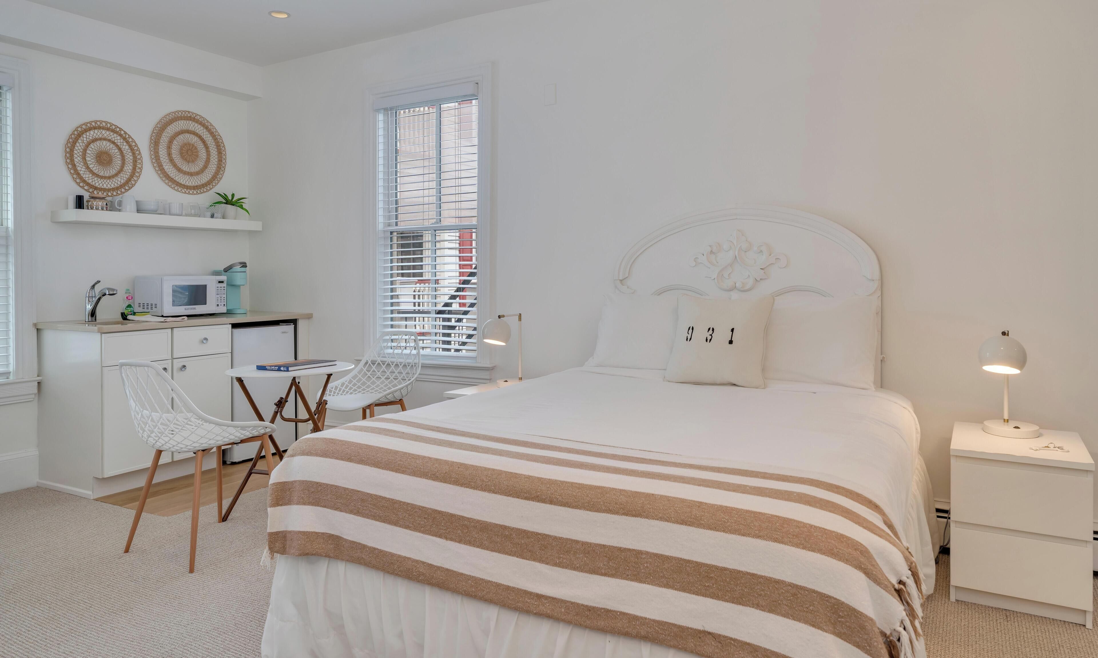 Une chambre à coucher au style minimaliste, comprenant un lit, des tables de chevet, un bureau et des chaises.