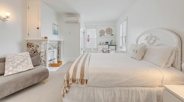 A bedroom with a large bed, a sofa, a fireplace, and a desk with a computer. - 931 Beach Guest House  (Cape May)