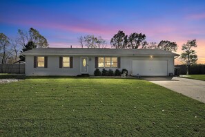A single-story house with a garage, a well-maintained lawn, and a clear sky.
