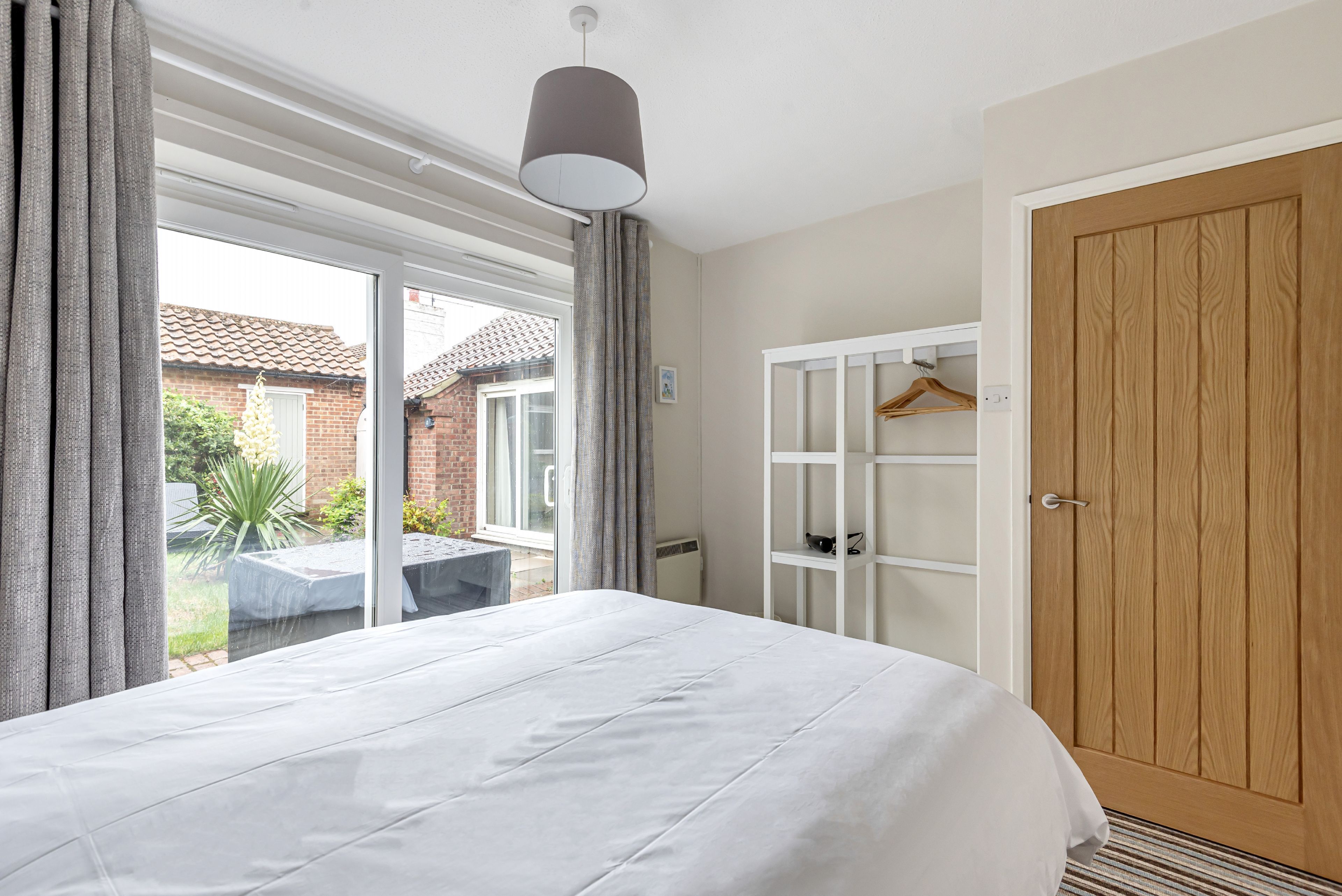A bedroom with a large bed, a wardrobe, and a hanging rack.