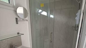 A bathroom with a glass-enclosed shower, a sink, and a mirror.