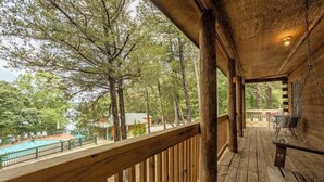 A wooden deck with a view of a swimming pool and trees. - Table Rock Lake Cabin - The Cedars #1 with Lake Access, Hot Tub, Outdoor Pool (Shell Knob)