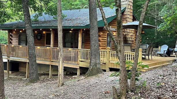 Un rustico chalet con una terrazza, immerso tra gli alberi.