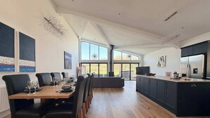 Una cuina moderna amb zona de menjador, grans finestres i vista cap a l'exterior.