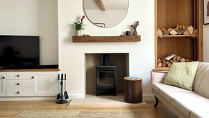 Ein Wohnzimmer mit Kamin, Fernseher, Sofa und Spiegel an der Wand.