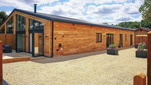 Um edifício moderno de madeira com janelas amplas e uma entrada com calçada de brita.