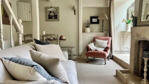 Een gezellige woonkamer met een bank, fauteuil en open haard.