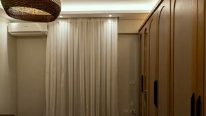 A hotel room with a bed, a wardrobe, a hanging light fixture, and a curtain. - Entire rental unit in Al Manteqah Ath Thamenah, Egypt (Cairo Governorate)