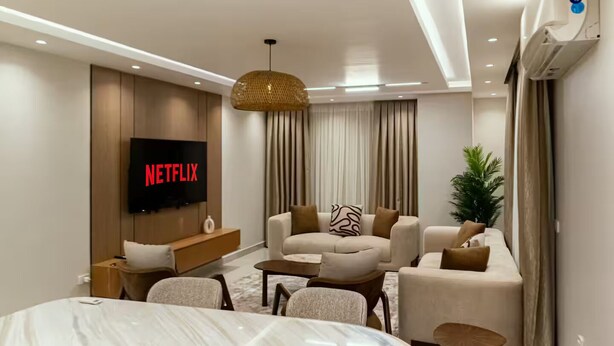 A modern living room with a large flat-screen TV displaying 'NETFLIX', a sofa set, a coffee table, and a small side table. - Entire rental unit in Al Manteqah Ath Thamenah, Egypt (Cairo Governorate)