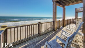 A wooden deck with a view of the ocean, featuring a railing and several chairs. - Inn Luxury North | Livin’ the Luxe Life (Surf City)