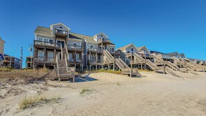 A beachfront property with multiple wooden houses connected by wooden walkways. - Inn Luxury North | Livin’ the Luxe Life (Surf City)