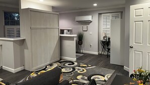 Un espacio habitable compacto con kitchenette, comedor y zona de estar con alfombra estampada.