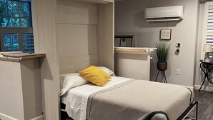 Un dormitorio moderno con cama, mesita de noche y un pequeño espacio de escritorio.
