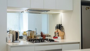 A modern kitchen with white cabinetry, a stainless steel stove, and various kitchen utensils. - Artsy 2BR 2BA Retreat in West Village, West End Brisbane (West End)