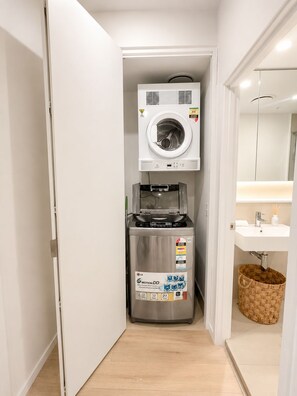 A laundry room with a washing machine, a dryer, and a small sink with a basket.