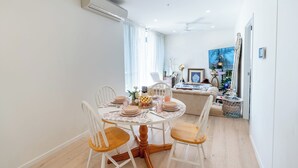 A dining area with a round table set for four, white chairs, and a white ceiling fan. - Artsy 2BR 2BA Retreat in West Village, West End Brisbane (West End)