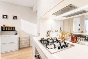 Una cocina moderna con estufa a gas, muebles blancos y una encimera con utensilios de cocina.
