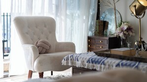 A well-lit room with a tufted armchair, a side table with a lamp, and a mirror on the wall. - Artsy 2BR 2BA Retreat in West Village, West End Brisbane (West End)