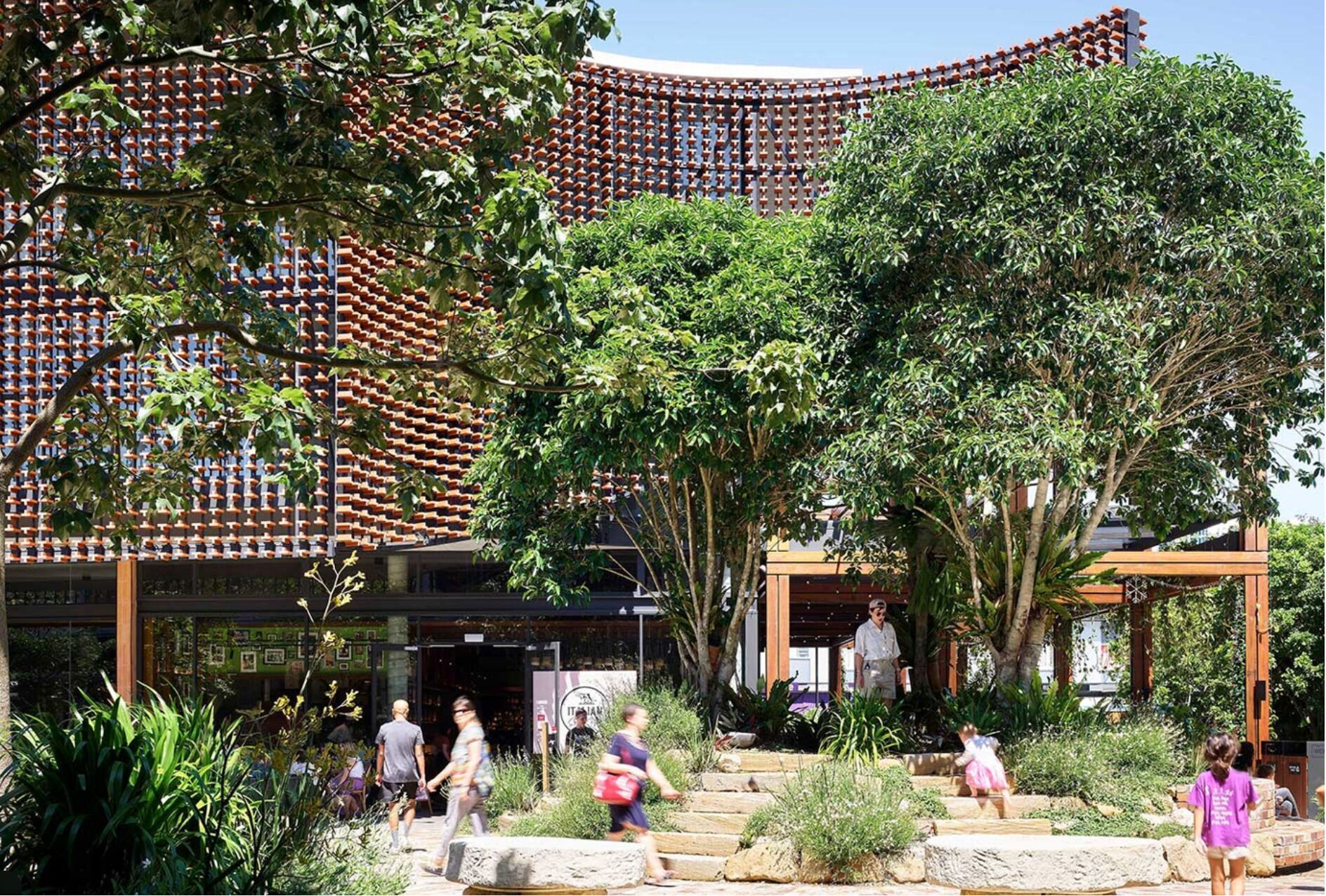 A courtyard with a traditional tiled wall, stone steps, and lush greenery.