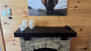 A fireplace with a stone surround and a highland cow picture above it. - Nice 2-bedroom cottage with AC in Mountain View (Mountain View)