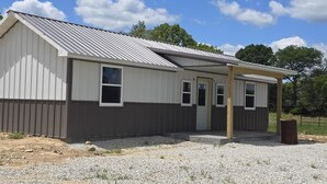 A single-story building with a metal roof, two windows, and a door. - Nice 2-bedroom cottage with AC in Mountain View (Mountain View)