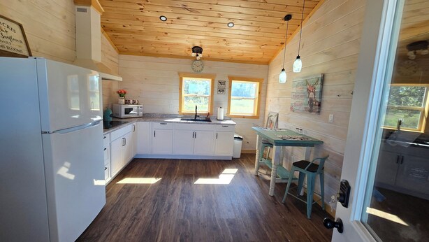 A kitchen with wooden walls, a central island, and a dining area with a table and chairs. - Nice 2-bedroom cottage with AC in Mountain View (Mountain View)