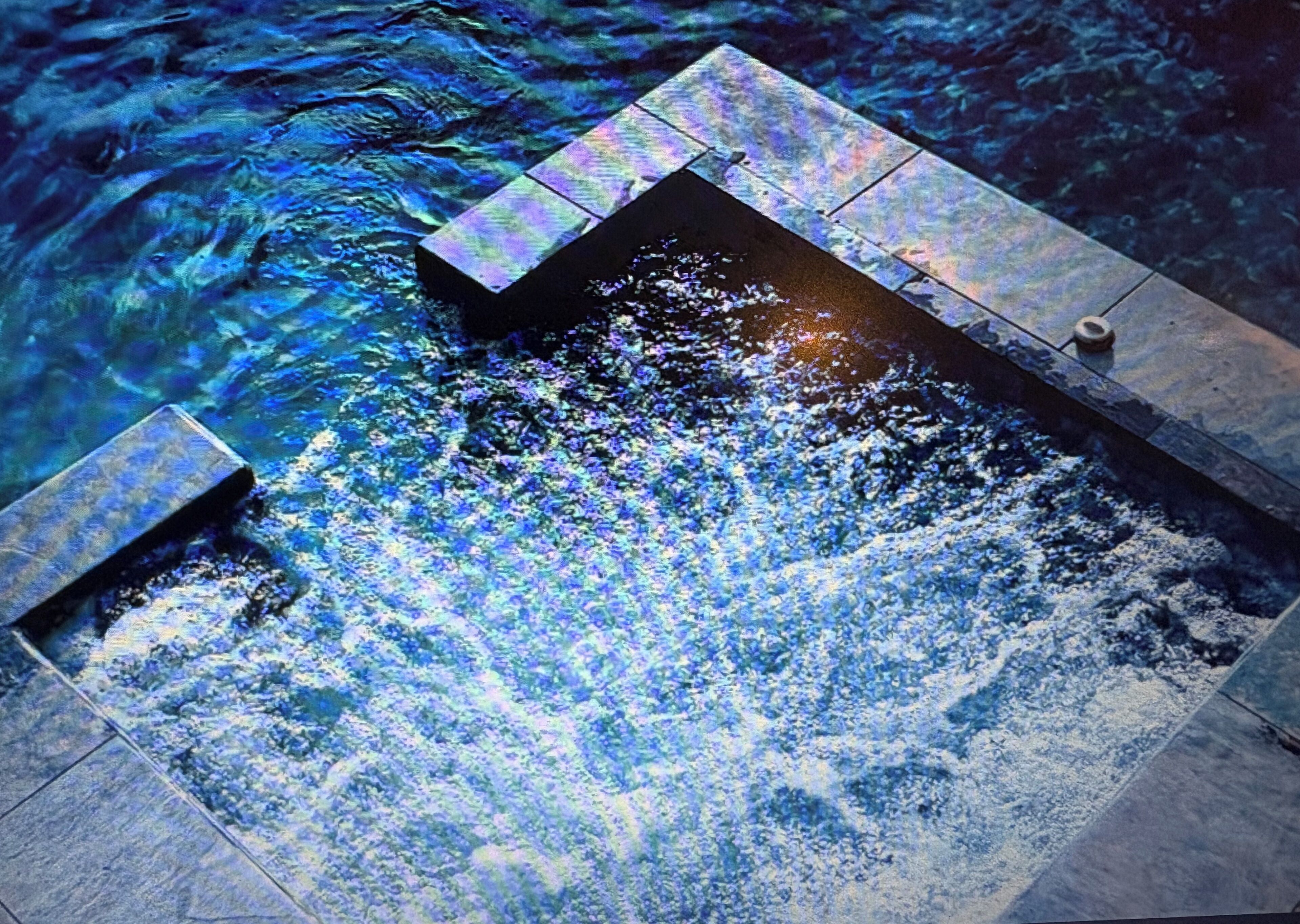 Une piscine à l’eau claire, avec un élément décoratif aquatique bien visible qui produit des éclaboussures.