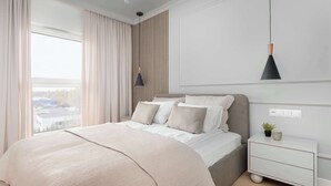 A bedroom with a bed, bedside table, and a hanging pendant light. - Spacious Apartment | Balcony and Private Parking in Garage (Łódź)