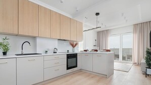 A modern kitchen with white cabinets, a black faucet, and a built-in oven. - Spacious Apartment | Balcony and Private Parking in Garage (Łódź)