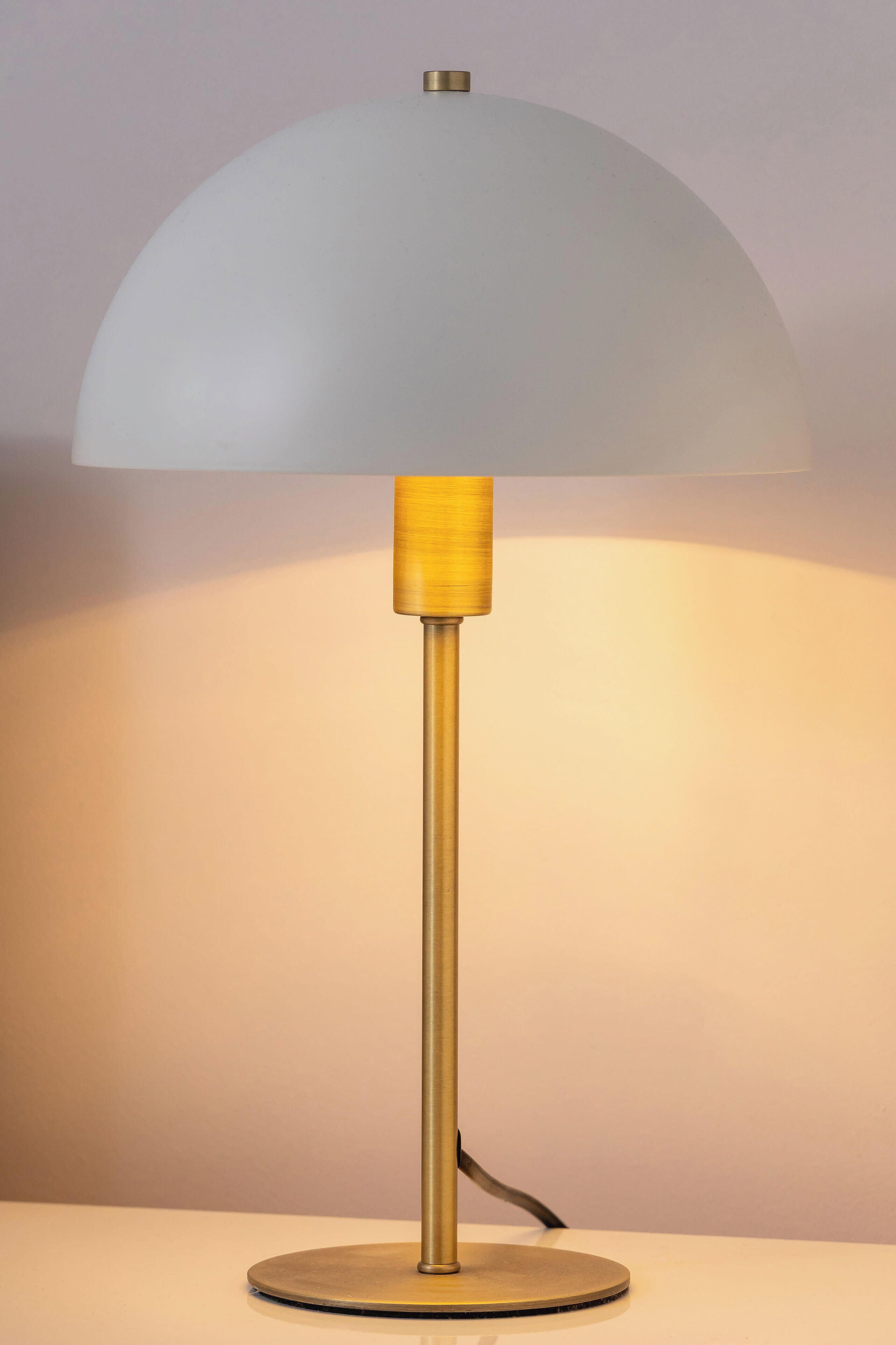 Un lampadaire avec un abat-jour blanc et un pied doré.