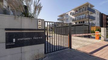 Una entrada cerrada a un complejo de apartamentos con un letrero que indica 'APARTMENTY POEZIL 16-18' y 'DOM100 EU'.