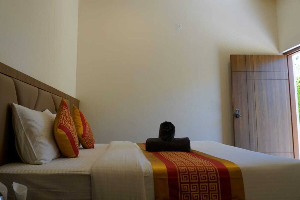 A hotel room with a bed, pillows, a towel, and a wardrobe.