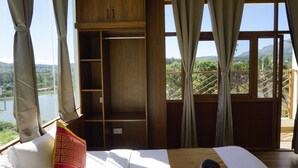 A bedroom with a wooden bed, a nightstand, and a window with curtains. - AT CKM Homestay (Chikkamagaluru)
